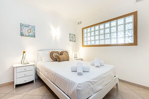 Una habitación de hotel con una cama, dos mesitas de noche, un ventanal con vistas y dos obras de arte colgadas en la pared.