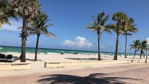 A beach with palm trees, a paved walkway, and the ocean in the background. - Sun Sand Retreat 1BR 1BA (Hollywood)