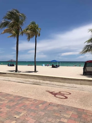 Ein Strand mit Palmen, blauem Himmel und Sand.