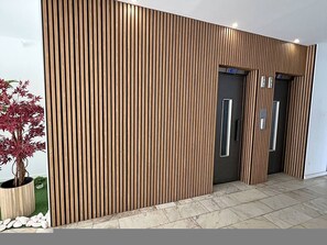 A modern building facade with vertical wooden slats, a potted plant, and a tiled floor. - Praia da Rocha Ac Pet Friendly Near the Beac (Portimão)