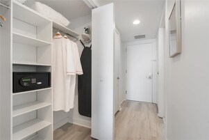 A walk-in closet with shelves, a hanging rack, and a digital lock.