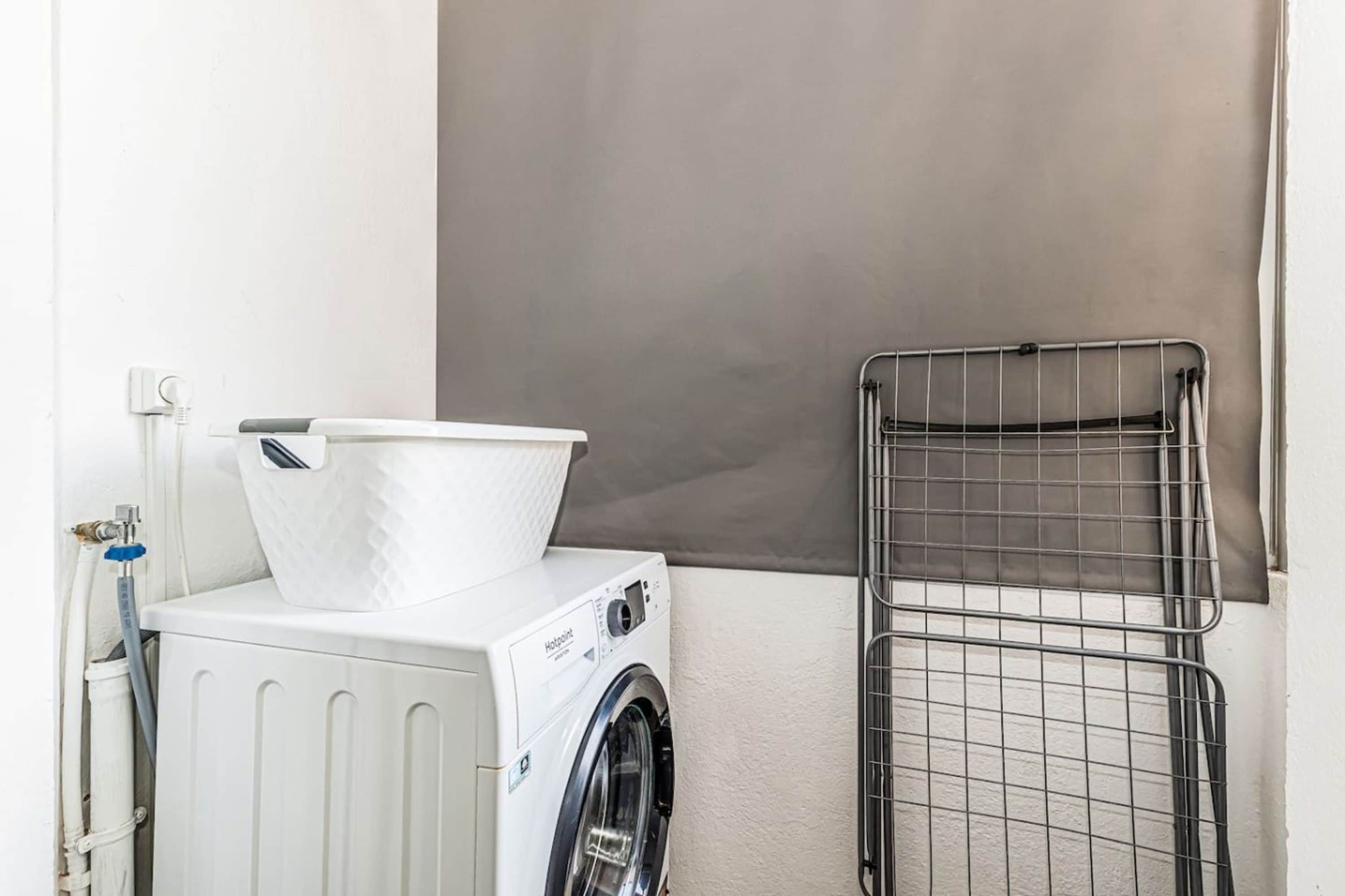A laundry area with a washing machine, a drying rack, and a towel rack.