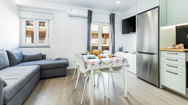 Un apartamento moderno con comedor, kitchenette y un sofá gris.