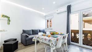Un espacio habitable moderno con comedor, sofá gris y balcón con vistas.