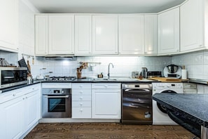 Eine moderne Küche mit weißen Schränken, Edelstahlgeräten und Holzboden.
