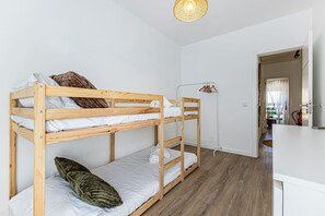 Ein Schlafraum mit Etagenbetten, Holzboden, weißen Wänden und einer Pendelleuchte.
