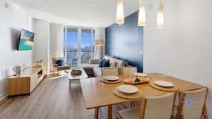 Ein modernes Wohnzimmer mit Essbereich, großen Fenstern und Blick auf die Stadt.