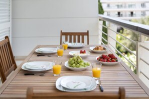 Ein Holztisch, gedeckt für das Frühstück, mit Tellern, Gläsern Orangensaft, einer Schüssel Trauben und einem Teller Erdbeeren.