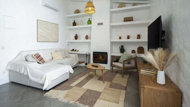 Una sala de estar moderna con un sofá, una mesa de centro, una chimenea y un televisor sobre un mueble.