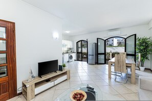 A modern living room with a television, a dining area, and a kitchen in the background. - Moinhos Location Pool Families and Couples (Lagos)