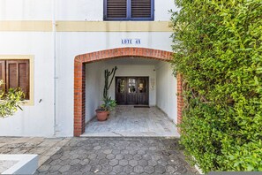 A building entrance with a brick archway, a potted plant, and a door with a sign above it. - Moinhos Location Pool Families and Couples (Lagos)