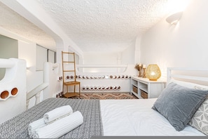 A bedroom with a bunk bed, a bedside table with a lamp, a mirror, and a wall-mounted shelf with decorative items. - Casa Saudade Pet Friendly Terrace Ferragudo (Lagoa)