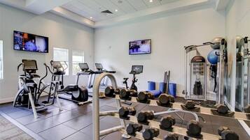 Un gimnasio con cintas de correr, bicicletas estáticas y equipo de levantamiento de pesas.