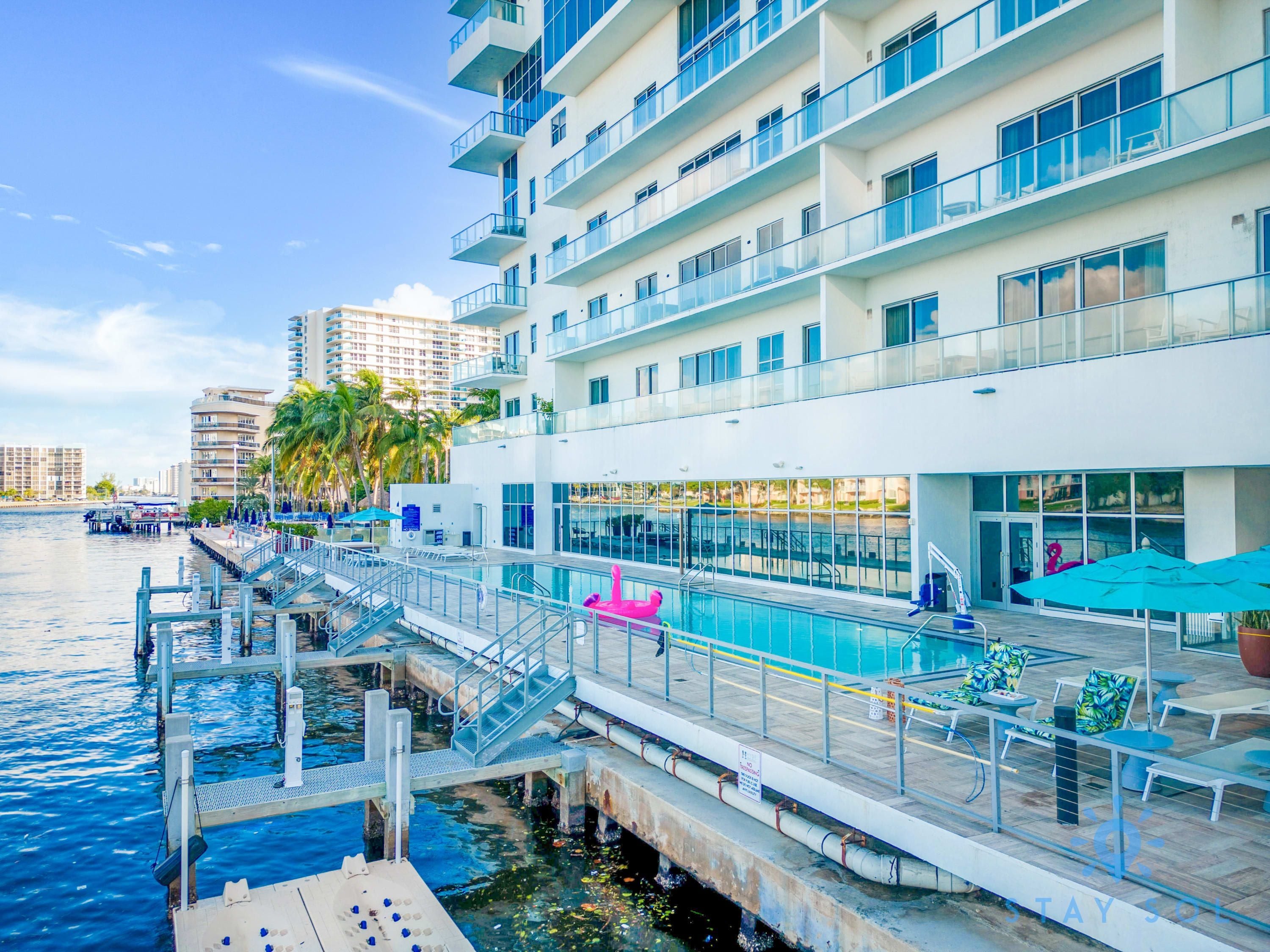 A waterfront hotel with a pool, outdoor seating, and a dock.