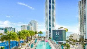 Ein Hotelpoolbereich mit einem langen, rechteckigen Pool, Liegestühlen und Palmen.
