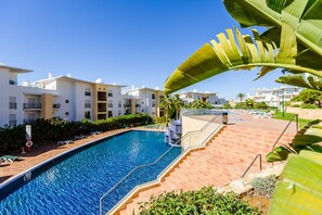 A swimming pool surrounded by a brick walkway, with a view of modern buildings in the background. - BnB Homes White Rose Garden Apartment 2 Terraces (Albufeira)
