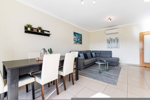 Ein modernes Wohnzimmer mit Essbereich, grauem Sofa und Couchtisch.