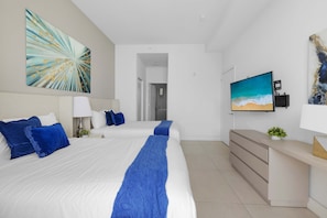 A hotel room with a large bed, a TV, a desk, and a painting on the wall. - 2BR Ocean View Balcony Pool (Hollywood)