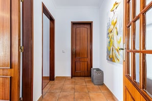 Ein Flur mit Holztüren, Fliesenboden und einer Tür mit Fensterteil.