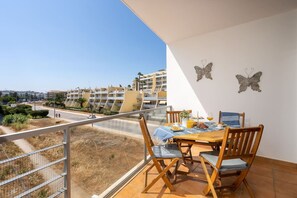 Ein Balkon mit Frühstückstisch, der auf ein Wohngebiet mit Gebäuden und einem klaren Himmel blickt.