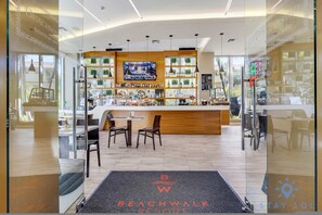 A modern bar area with a TV screen, shelves of bottles, and a seating area with chairs. - Spectacular Near Beach - 2 BR Apartment (Hallandale Beach)