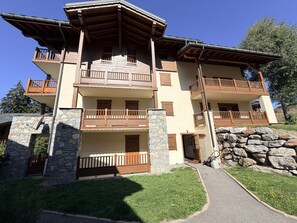 Un edificio de varios pisos con balcones, cimientos de piedra y cielo despejado.