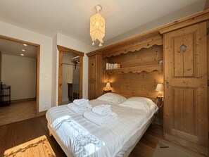 Une chambre à coucher avec un grand lit, une tête de lit en bois, des lampes de chevet et une armoire.