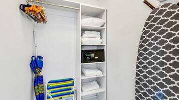 A hotel room with a white wardrobe, a digital safe, a striped towel, and a patterned curtain.