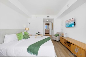 A hotel room with a bed, a desk, a TV, and a view of the sea. - Urban Apartment Balcony Pool (Hallandale Beach)