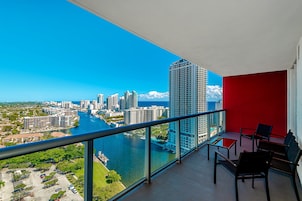 Un balcón con vista a la ciudad, sobre un río y edificios altos.