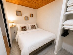 A bedroom with a bed, bedside tables, and a wall-mounted shelf with towels. - Le Cygne - 6-guest balcony apartment (Les Deux Alpes)