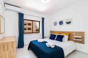 A modern bedroom with a bed, a window, and artwork on the wall. - Iberlagos Casa Luna Sea View Dona Ana Beach (Lagos)