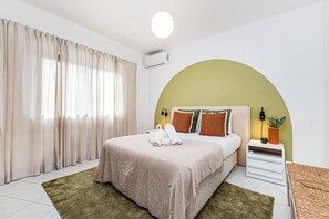 A bedroom with a bed, curtains, a bedside table, a lamp, and a wall-mounted air conditioner. - Casa do Vale Private Pool Pet Friendly (Lagoa)