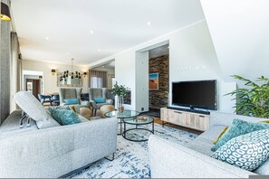 A modern living room with a sofa, armchairs, a coffee table, and a television. - Casa Corsino Private Pool Countryside (Monchique)