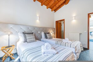 A hotel room with two beds, a wooden ceiling, a radiator, and a door leading to a balcony. - Casa Corsino Private Pool Countryside (Monchique)