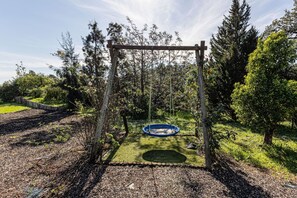 A wooden swing set with a blue swing, surrounded by trees and a grassy area. - Casa Corsino Private Pool Countryside (Monchique)