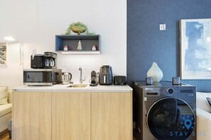 A compact kitchenette with a microwave, coffee maker, toaster, and a washing machine. - 1BR Apartment With Pool gym and Balcony (Miami)