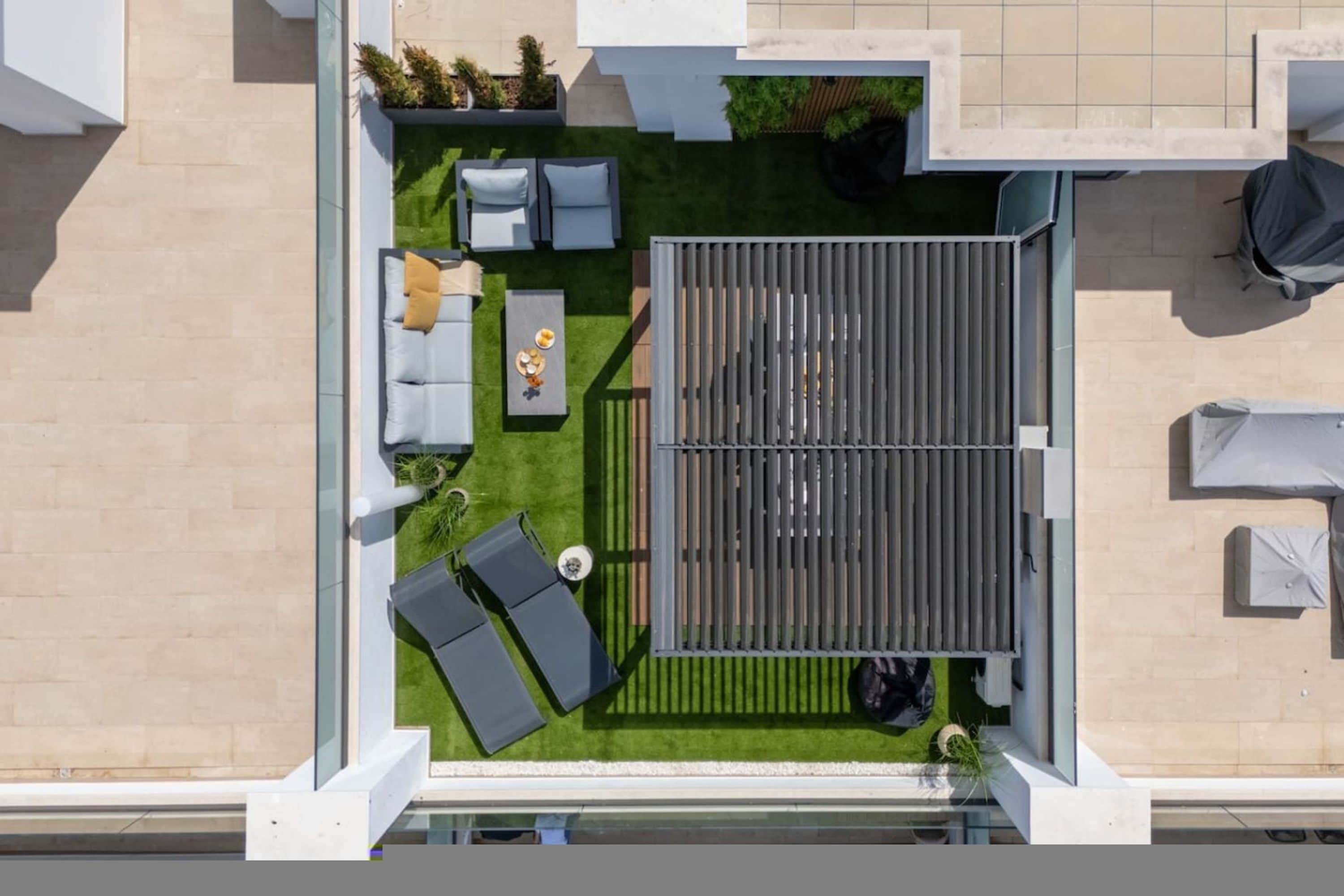 A rooftop terrace with a seating area, a small table, and a covered space.