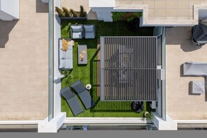 A rooftop terrace with a seating area, a small table, and a covered space. - Ria Terrace House Pool BBQ Terrace (Portimão)