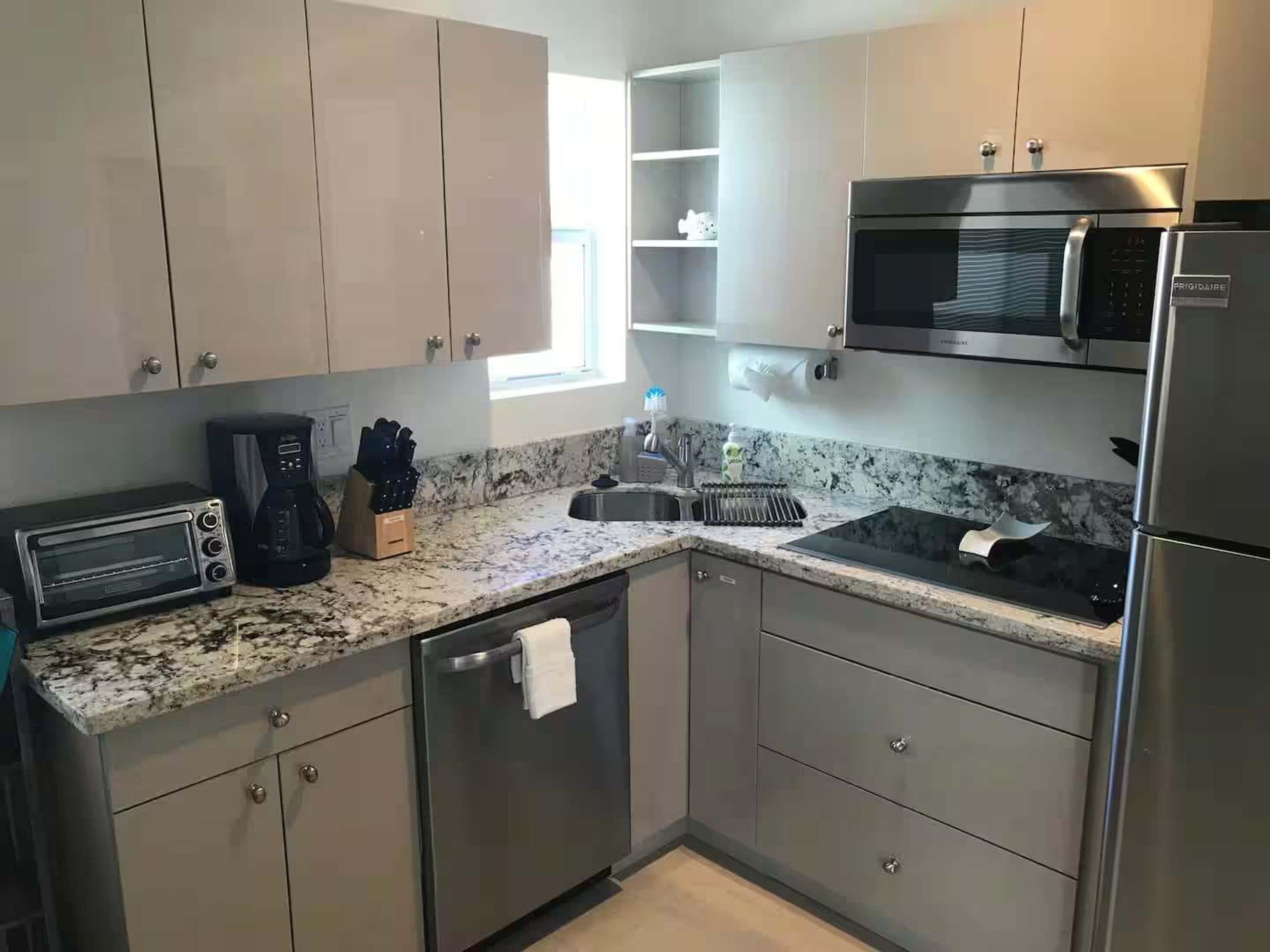 A modern kitchen with stainless steel appliances, a microwave, a toaster, and a coffee maker.