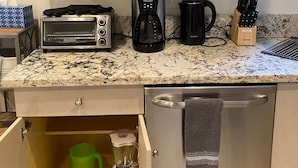 A kitchen with a toaster, coffee maker, and a blender on the counter, and cabinets above with dishes and glasses. - Beachside Comfort 2BR and 2BA With Outdoor Dining (Hollywood)