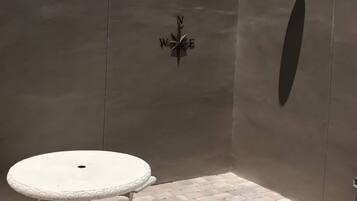 A patio area with a round table and benches, a compass decoration on the wall, and a wall-mounted light fixture.