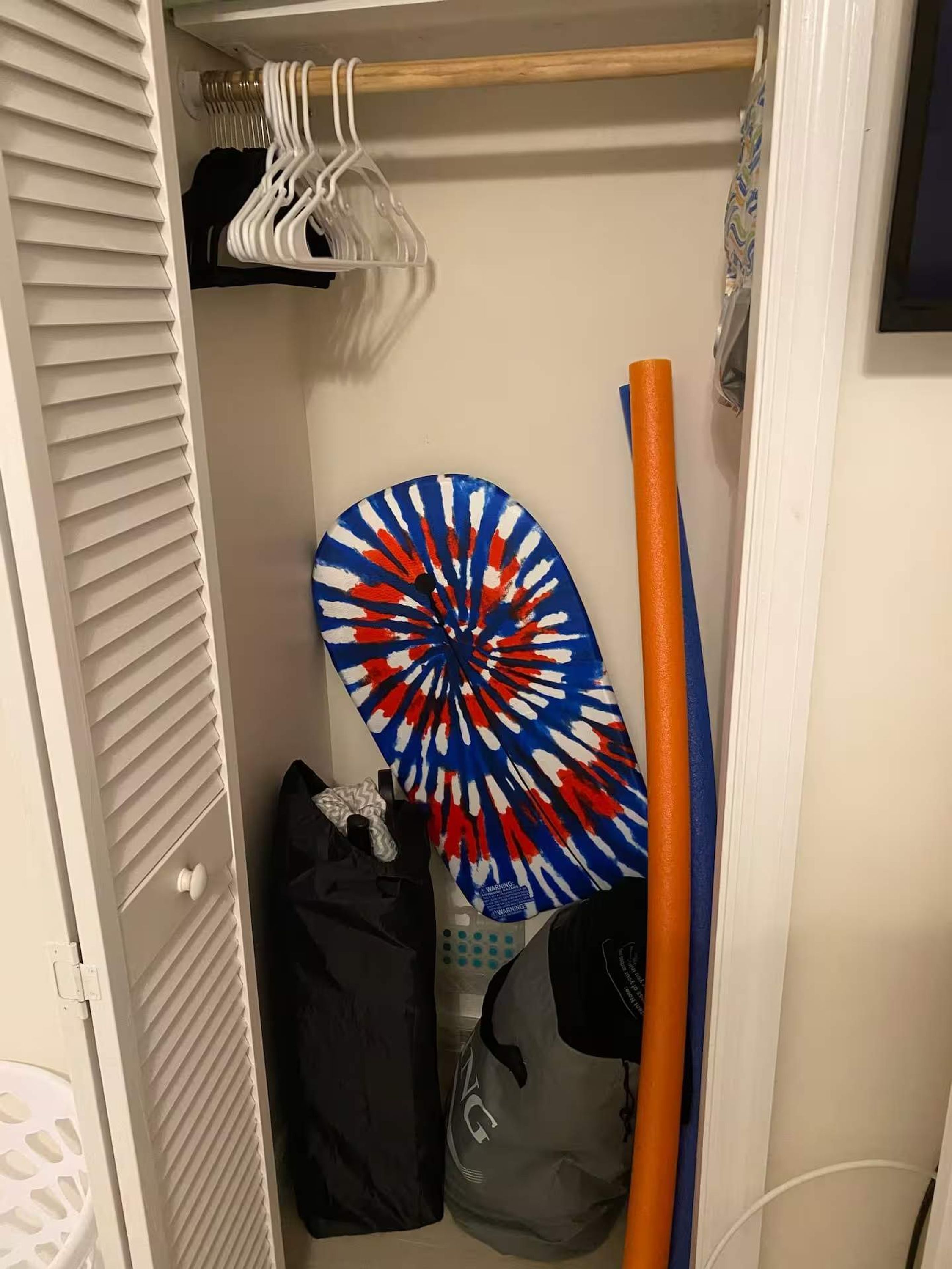 A closet with hanging clothes, a circular object, and a bag.