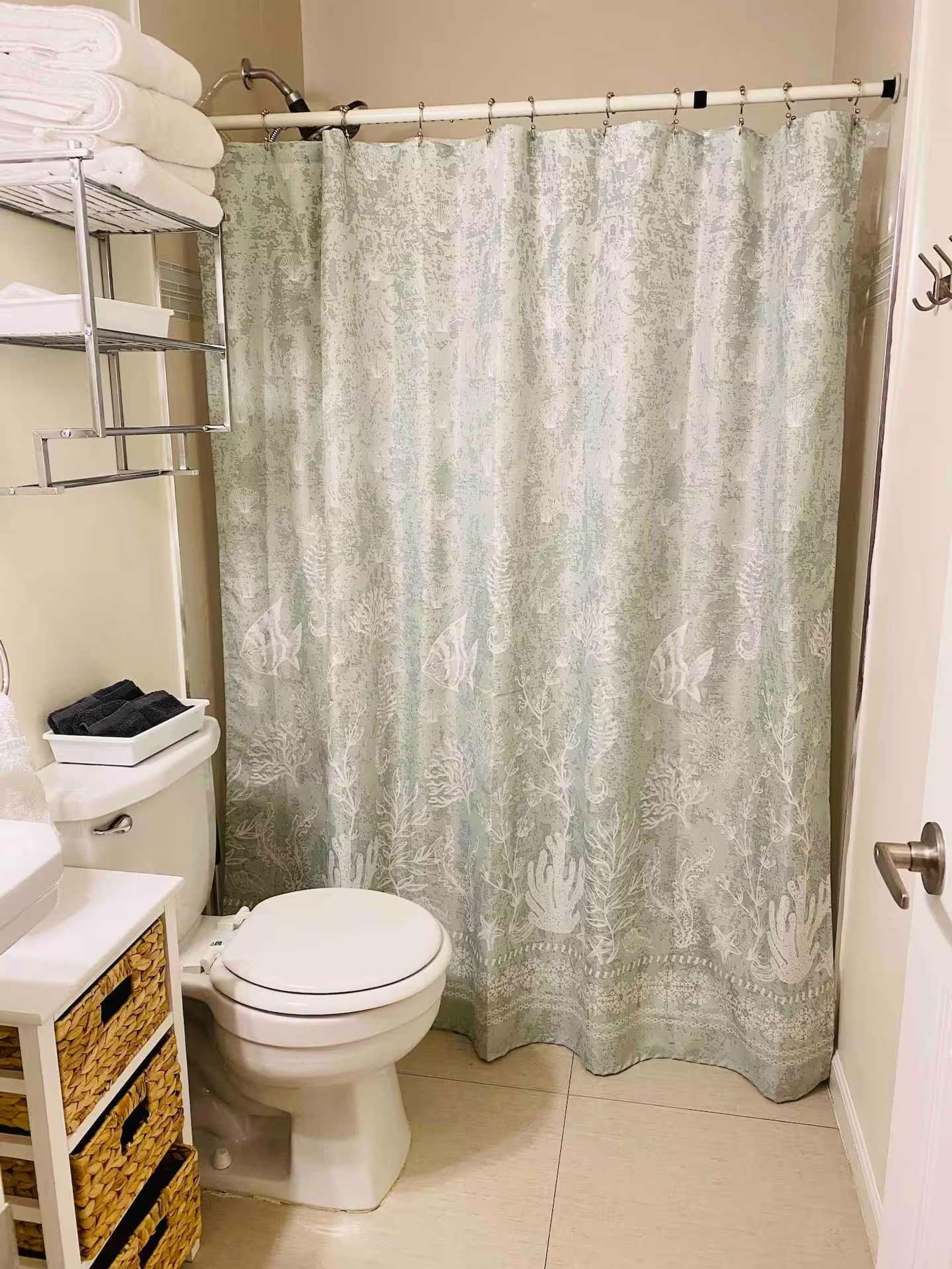 A bathroom with a toilet, a sink, a towel rack, and a shower curtain.
