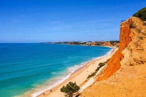 A coastal beach with clear blue waters, sandy shore, and a rocky cliff. - BnB Homes Duplex Apartment With 2 Bedrooms (Lagoa)
