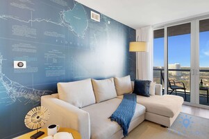 Una sala de estar moderna con un gran mural de mapa, un sofá, una mesa de centro y vistas de la ciudad desde el balcón.