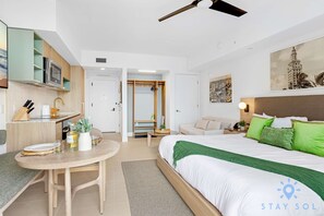 Ein Hotelzimmer mit einem Bett, einem Schreibtisch, einem Stuhl, einem Esstisch, einer Küchenzeile und einem Kleiderschrank.