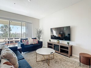 A modern living room with a sofa, a coffee table, and a flat-screen TV mounted on the wall.