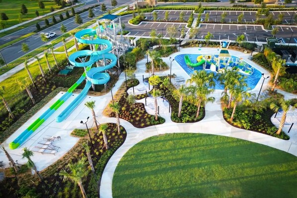 An aerial view of a water park with multiple slides and pools, surrounded by landscaped areas and parking.