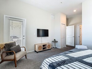 Une chambre à coucher avec un lit, une télévision, une chaise, une petite table et une porte.